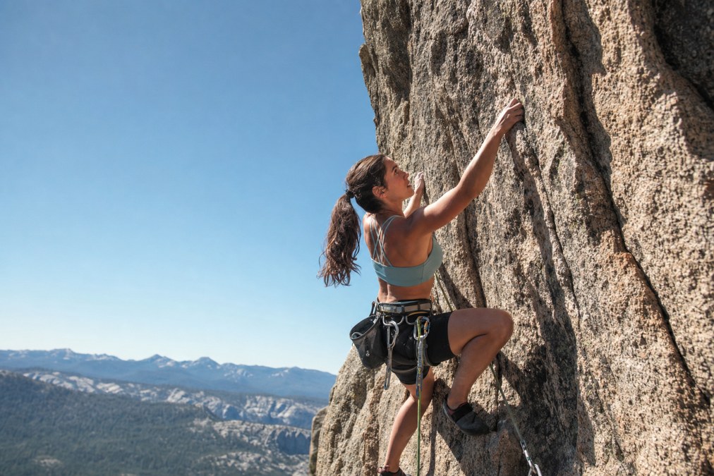 Woman climber wearing a harness on an outdoor rock wall