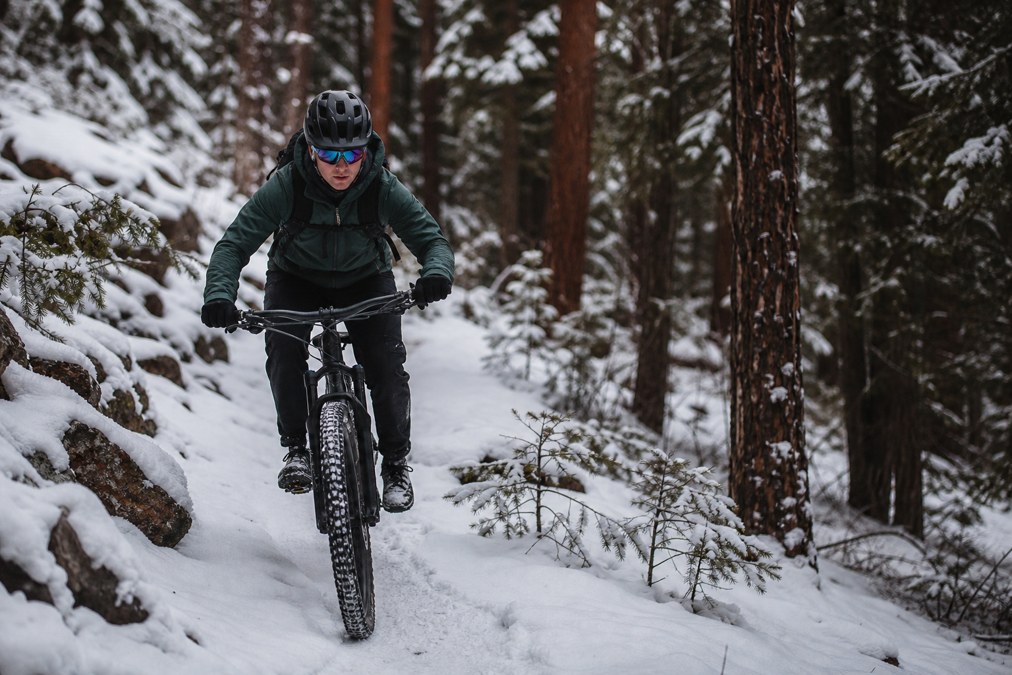 Mountain biker in cold-weather gear on a snowy trail