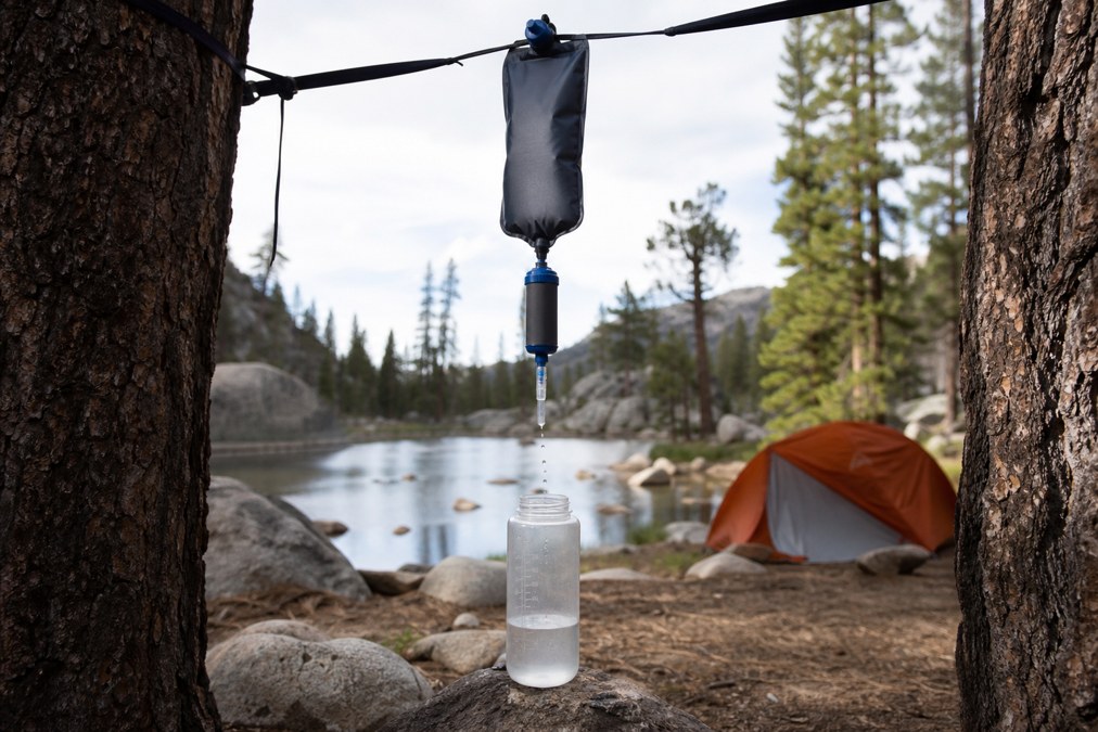 Gravity water filter hanging between trees at a backcountry camp