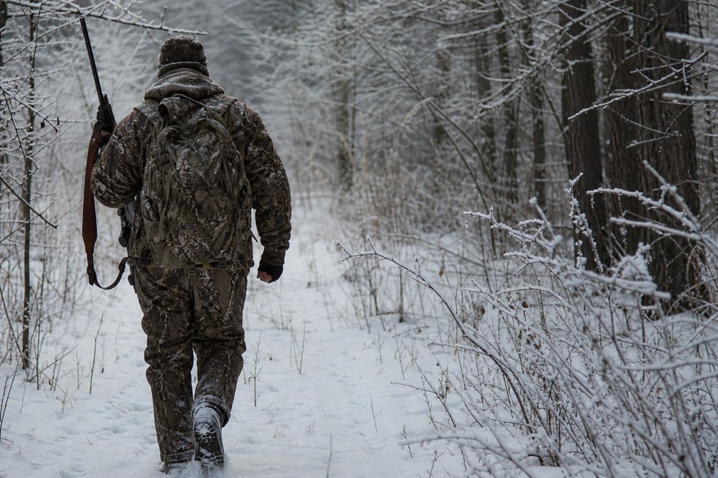 Hunter wearing insulated camo pants in snowy woodland