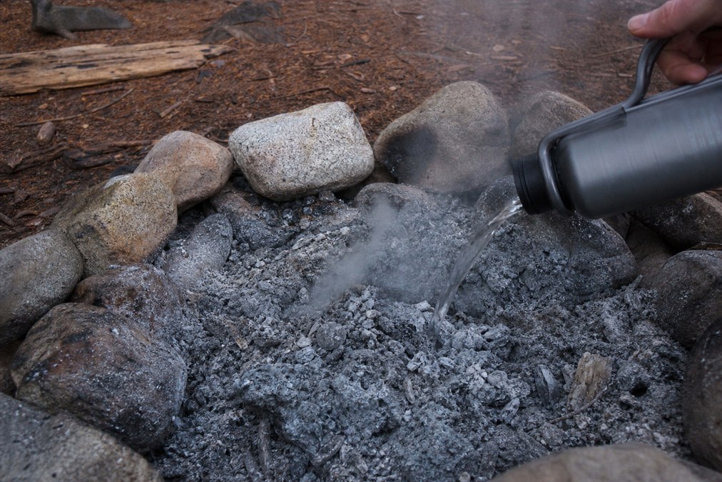 Established stone fire ring with drowned-out cold white ash after proper Leave No Trace extinguishing