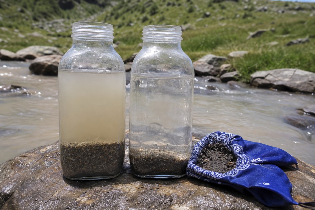 Cloudy silty creek water settling next to clearer water after a bandana sediment pre-filter at a mountain stream
